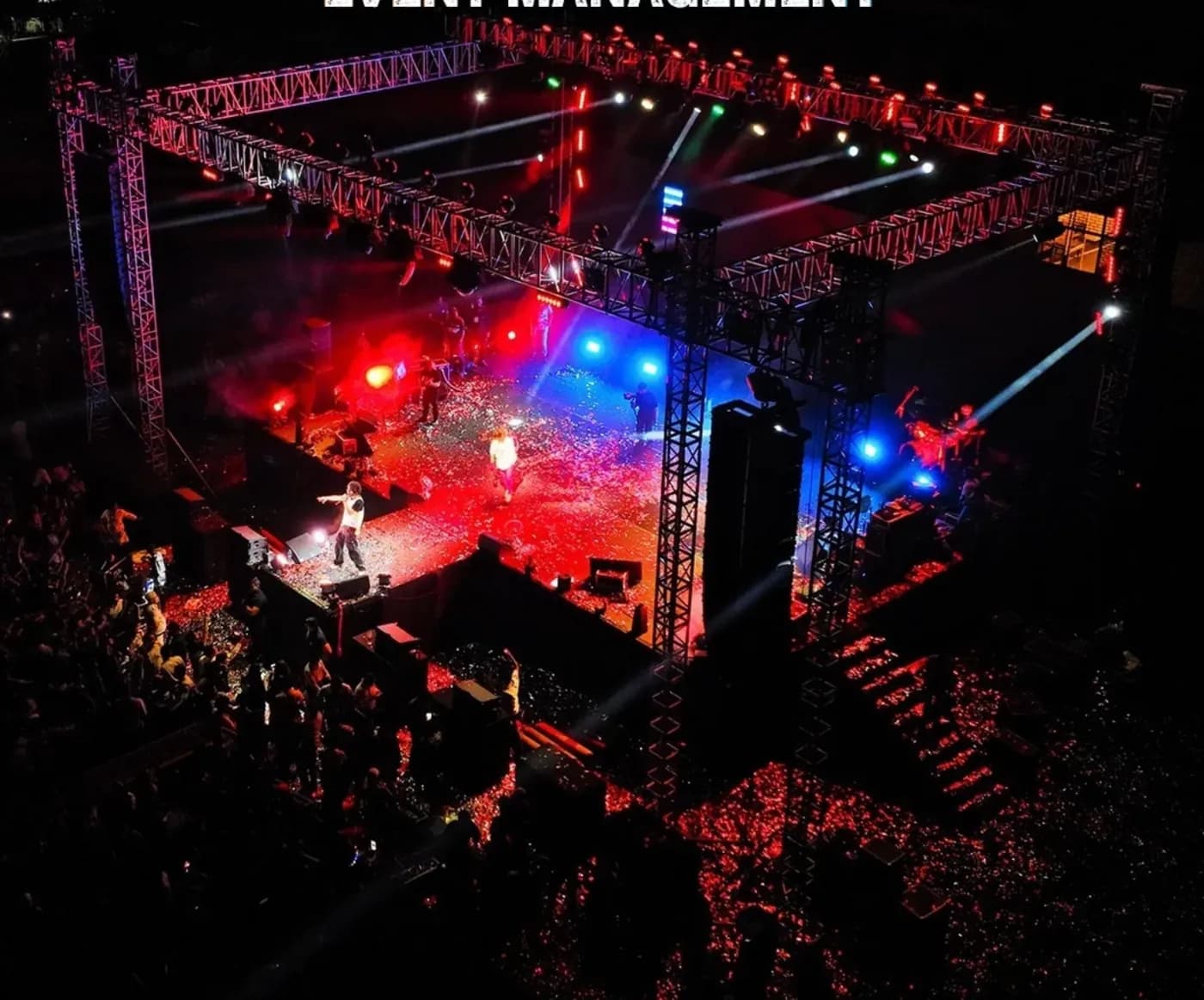 Aerial view of a concert stage lit in red and blue with the crowd below
