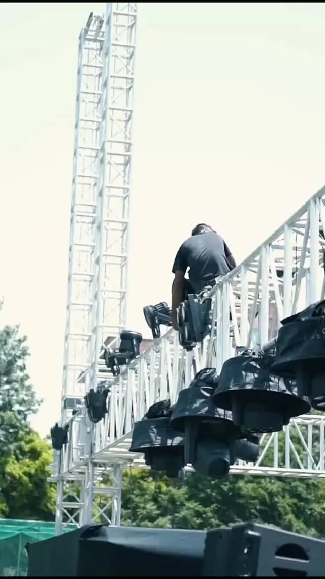Crew rigging speakers on a stage truss tower