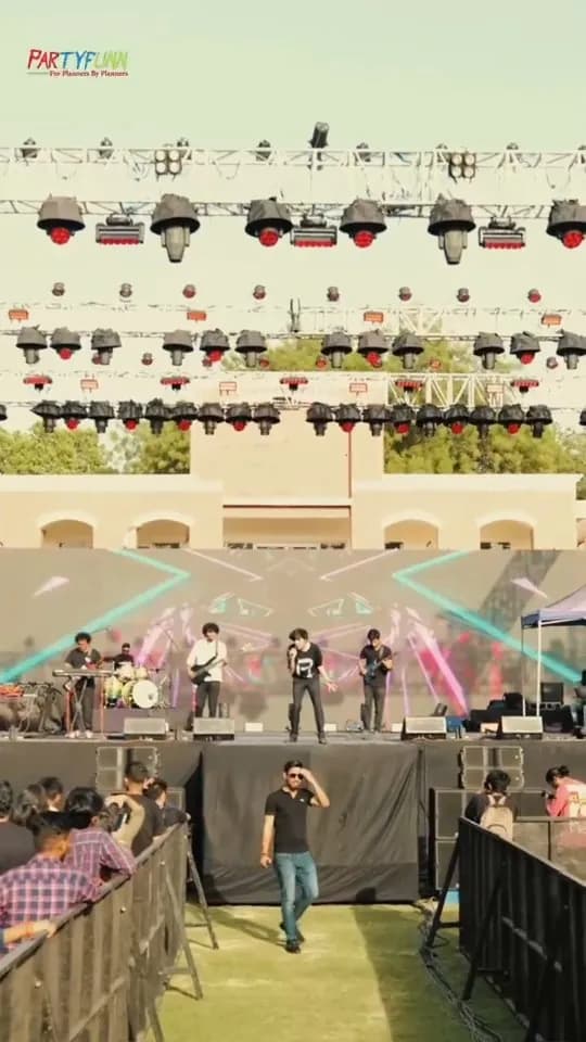 Band performing on an outdoor festival stage with full lighting rig