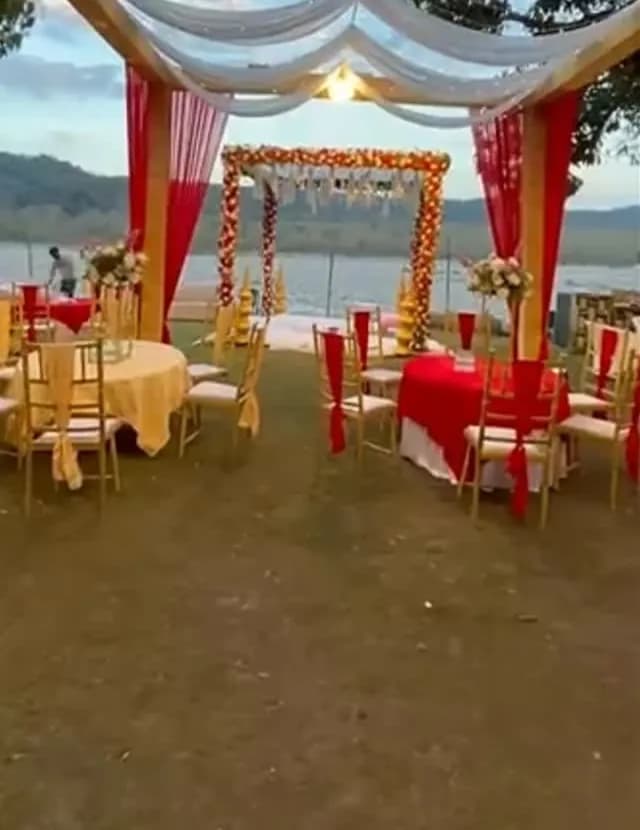 Lakeside destination wedding set-up with draped canopy and floral arch
