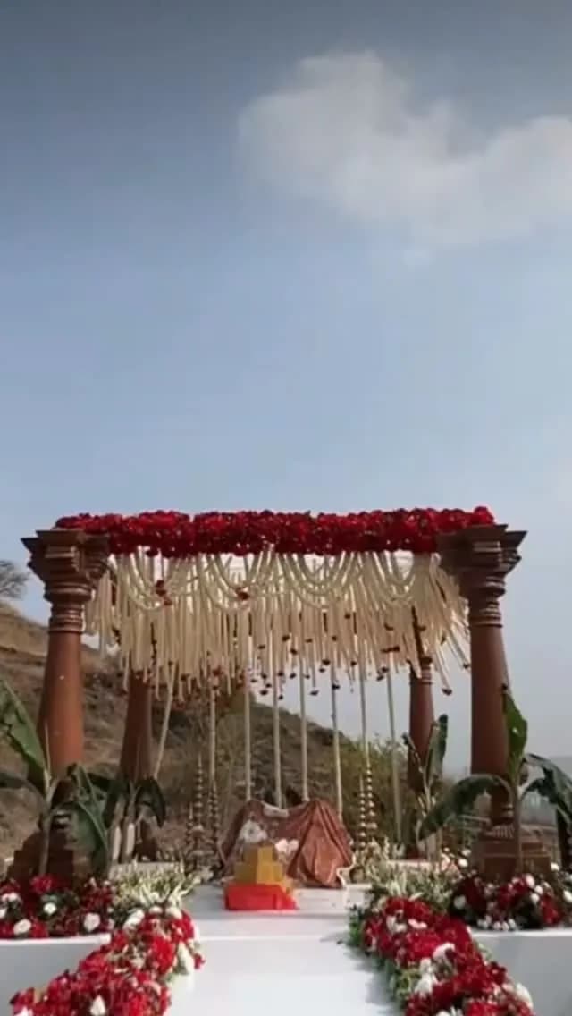 Hilltop wedding mandap decorated with red roses and marigold strings